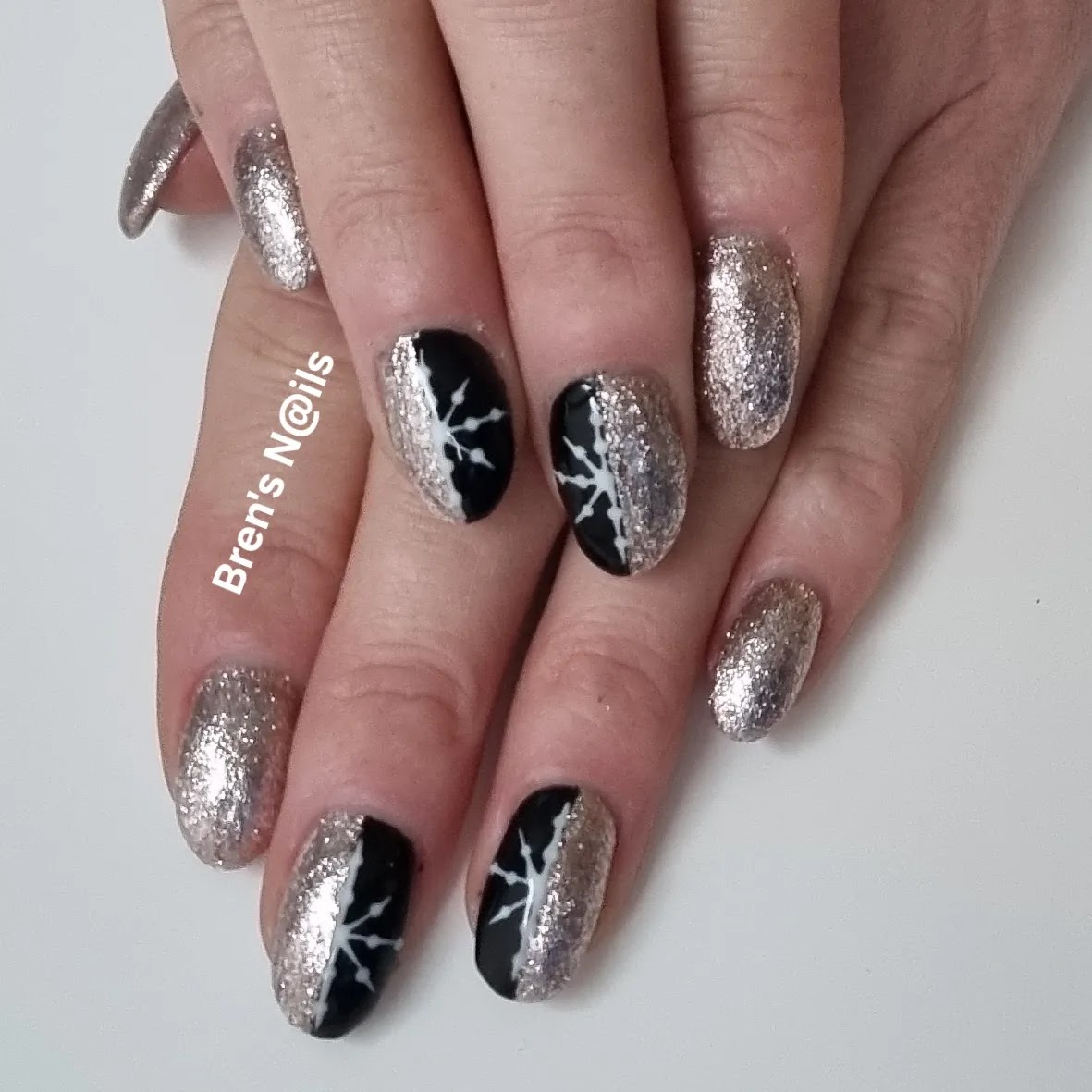 Zilveren glitternagels met zwarte nagels en witte sneeuwvlokken
